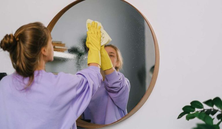 Mulher limpando o espelho com pano